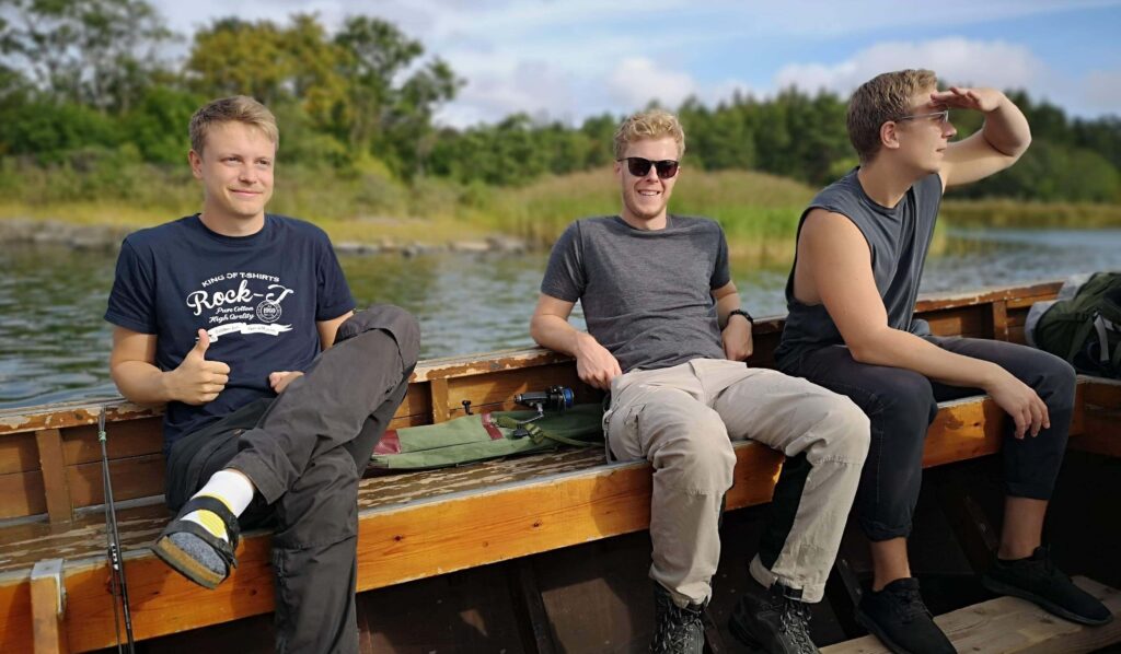 Tre killar i en passbåt på väg till Rävsten för att tälta i Stockholm